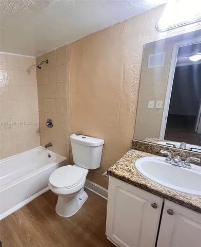 a bathroom with a granite countertop toilet a sink and a mirror