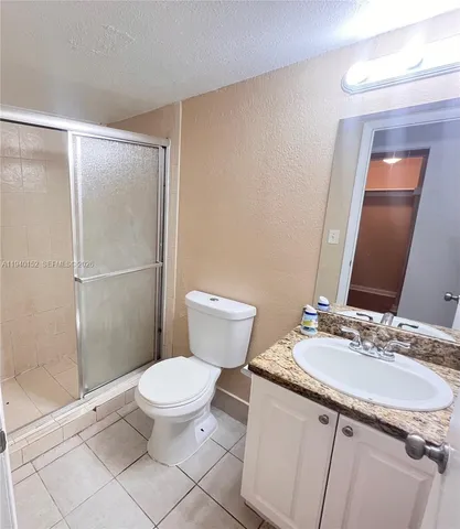 a bathroom with a sink a toilet a mirror and shower