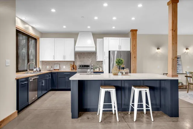 a kitchen with stainless steel appliances granite countertop wooden cabinets a sink a stove a dining table and chairs