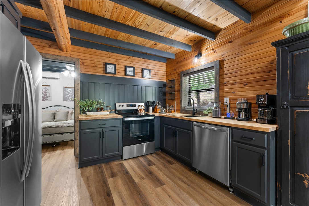 3931 Zack Road Marshall, AR 72650 - Photo 48 of 56 Kitchen with wooden counters, stainless steel appliances, wood walls, dark wood-type flooring, and a wood ceiling with exposed beams