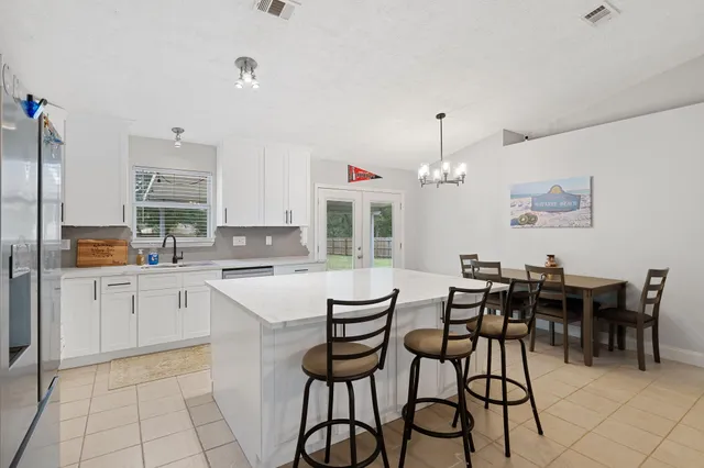 a kitchen with a dining table chairs and white cabinets