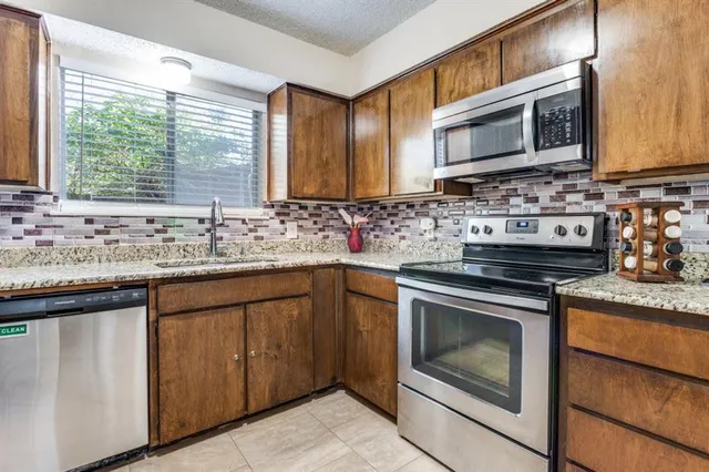 a kitchen with stainless steel appliances granite countertop a sink stove and microwave