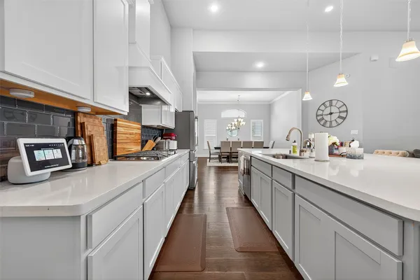 a large kitchen with kitchen island a stove a sink a oven a dining table and chairs