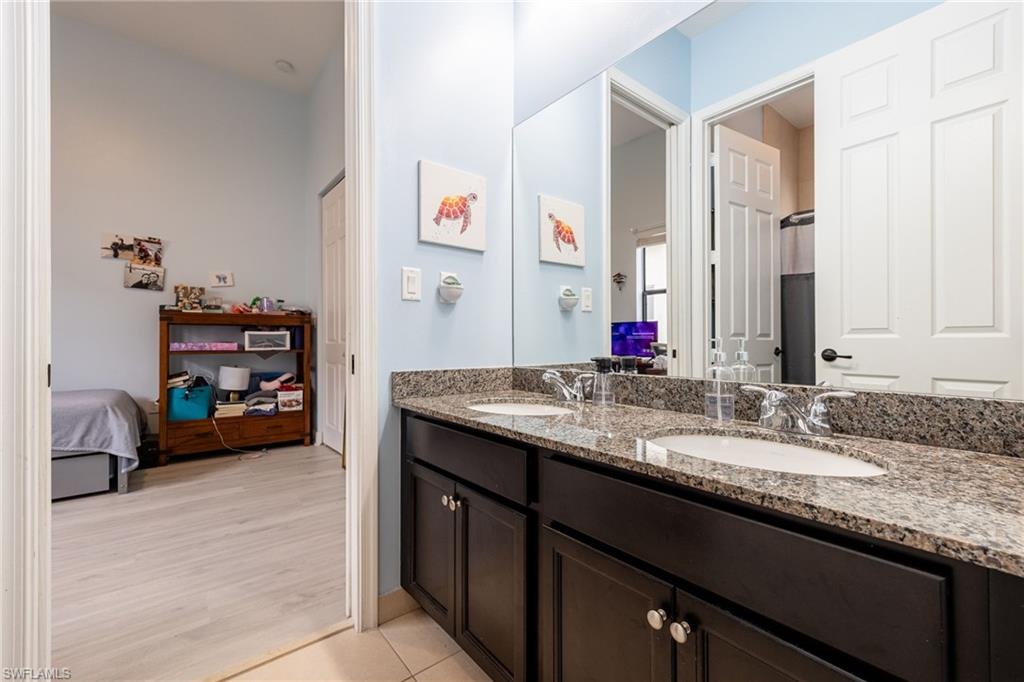 5116 Salerno Street Ave Maria, FL 34142 - Photo 23 of 36 a bathroom with a granite countertop sink a vanity and a mirror