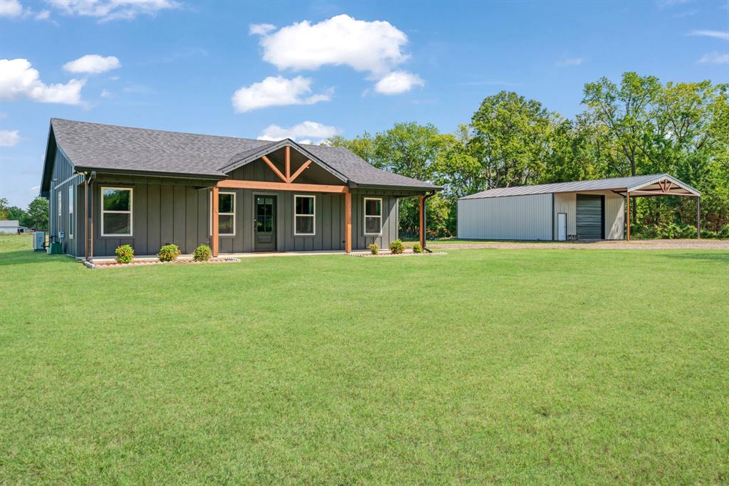 302 County Road Paris, TX 75462 - Photo 1 of 1 View of front of property featuring an outbuilding, board and batten siding, a porch, and a front yard