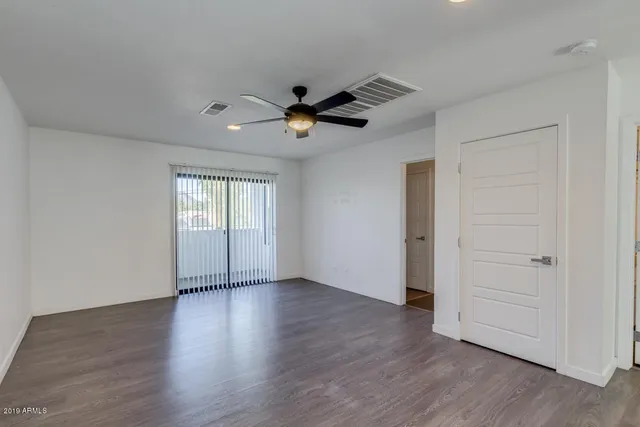 a view of an empty room with a window and wooden floor