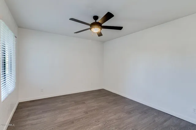 a view of empty room with wooden floor and ceiling fan