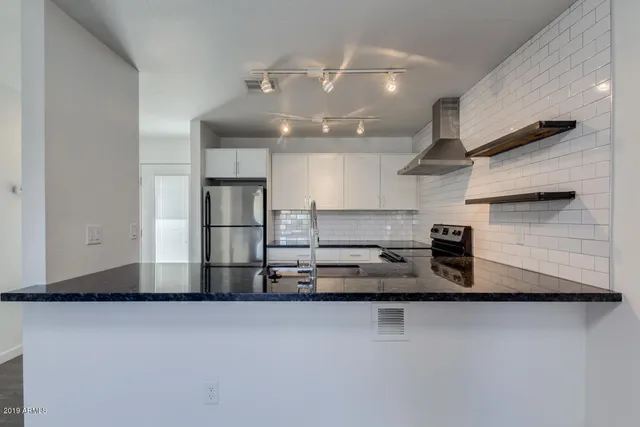 a kitchen with stainless steel appliances granite countertop a sink a stove and a refrigerator