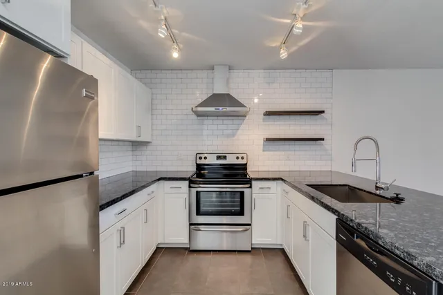 a kitchen with stainless steel appliances granite countertop a sink stove and refrigerator