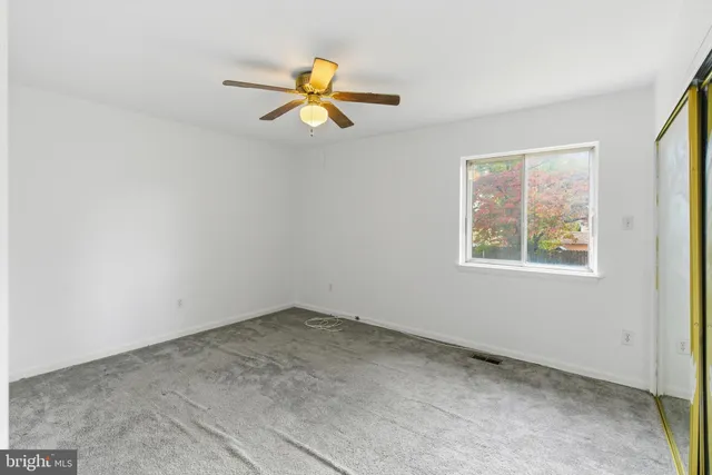 an empty room with a window and a ceiling fan