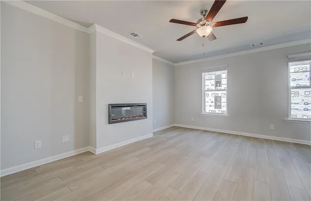 an empty room with windows and a ceiling fan