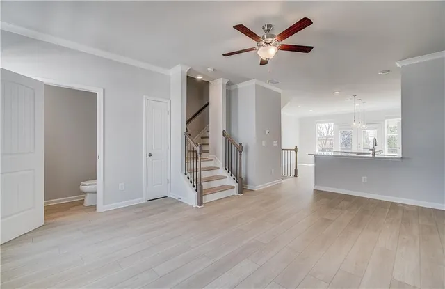 a view of an empty room with wooden floor and a ceiling fan