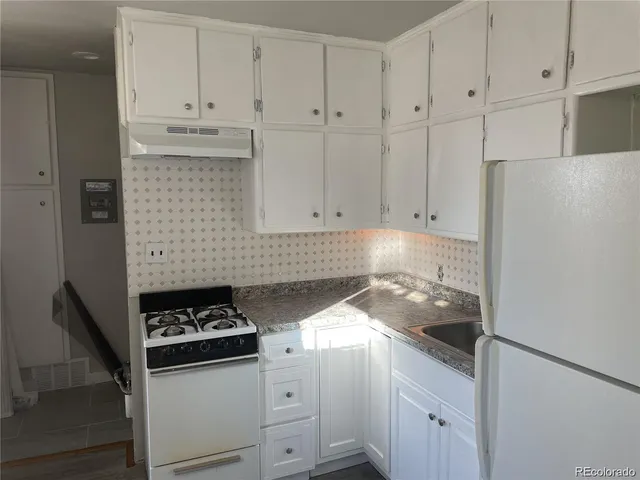 a kitchen with granite countertop white cabinets and white appliances