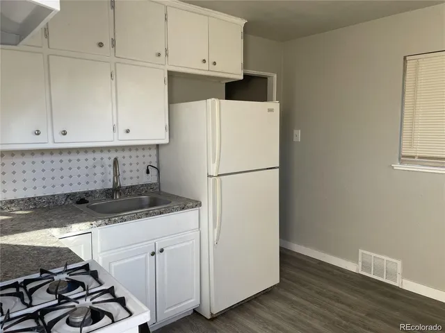 a kitchen with granite countertop a sink stove and white cabinets