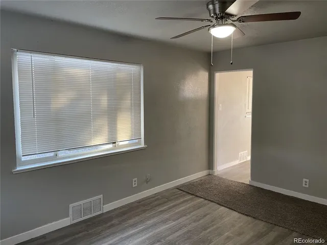 an empty room with wooden floor fan and windows