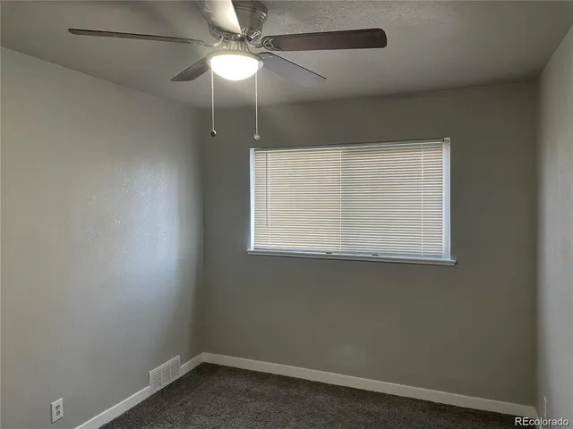 an empty room with a window and a fan