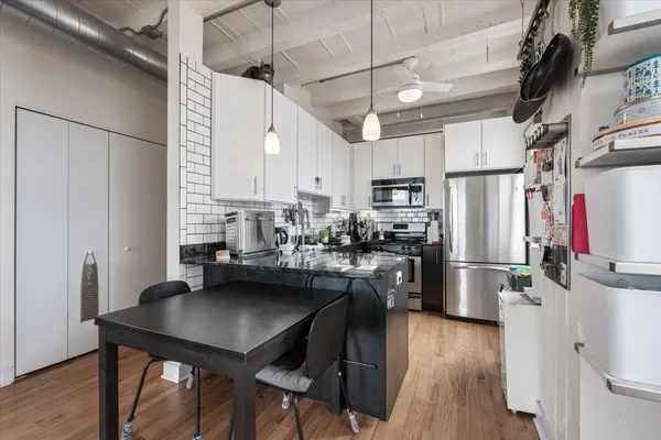 a kitchen with refrigerator and wooden floor