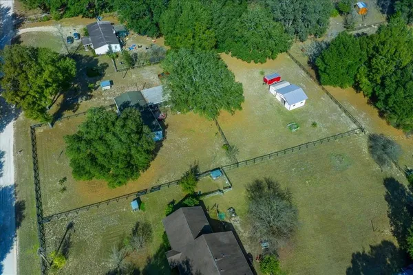 an aerial view of residential house with outdoor space and trees all around