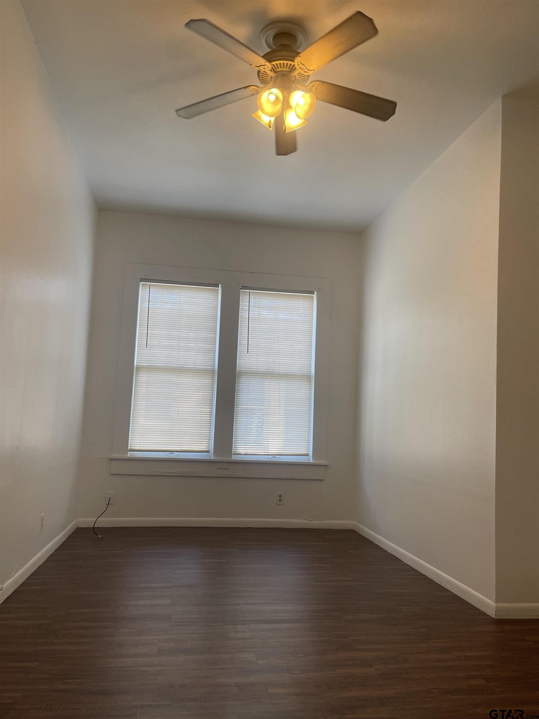 306 South Fenton Avenue Tyler, TX 75702 - Photo 11 of 11 an empty room with wooden floor chandelier fan and windows