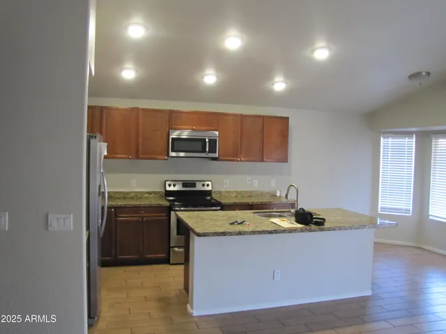 a kitchen with stainless steel appliances granite countertop a sink a stove and a refrigerator