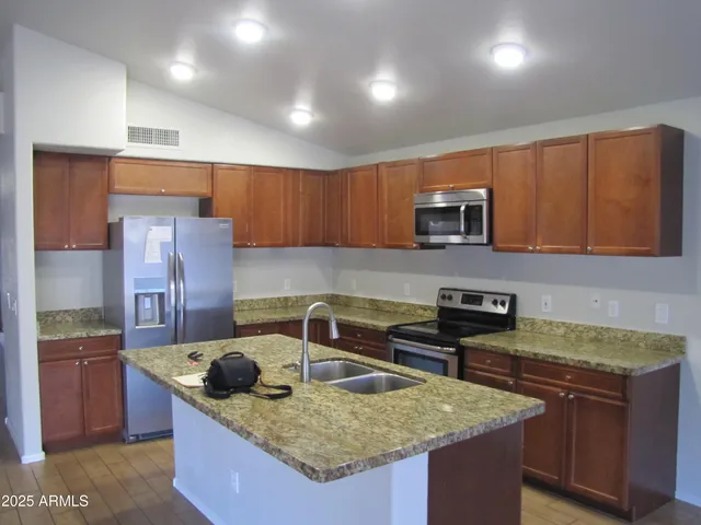 a kitchen with granite countertop a sink a stove and a wooden cabinets