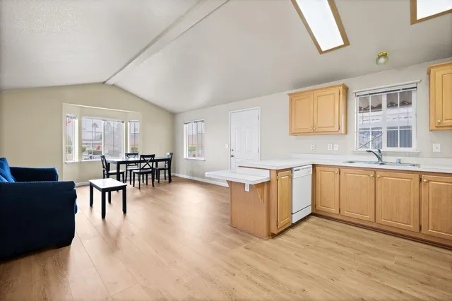 a large white kitchen with granite countertop a stove a sink a dining table and chairs