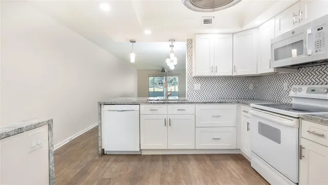 a kitchen with granite countertop white cabinets and white appliances