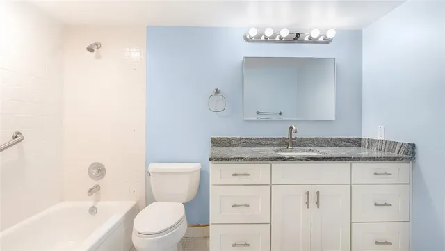a bathroom with a granite countertop sink a toilet and a mirror
