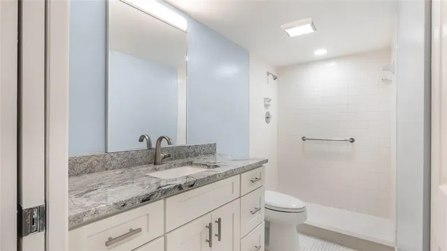 a bathroom with a granite countertop sink toilet and shower