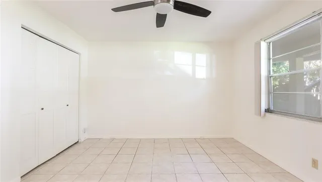 an empty room with windows and fan