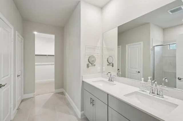 a bathroom with a double vanity sink mirror and next to a white cabinet
