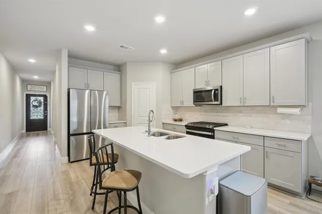 a kitchen with stainless steel appliances a stove a sink a microwave a refrigerator and cabinets