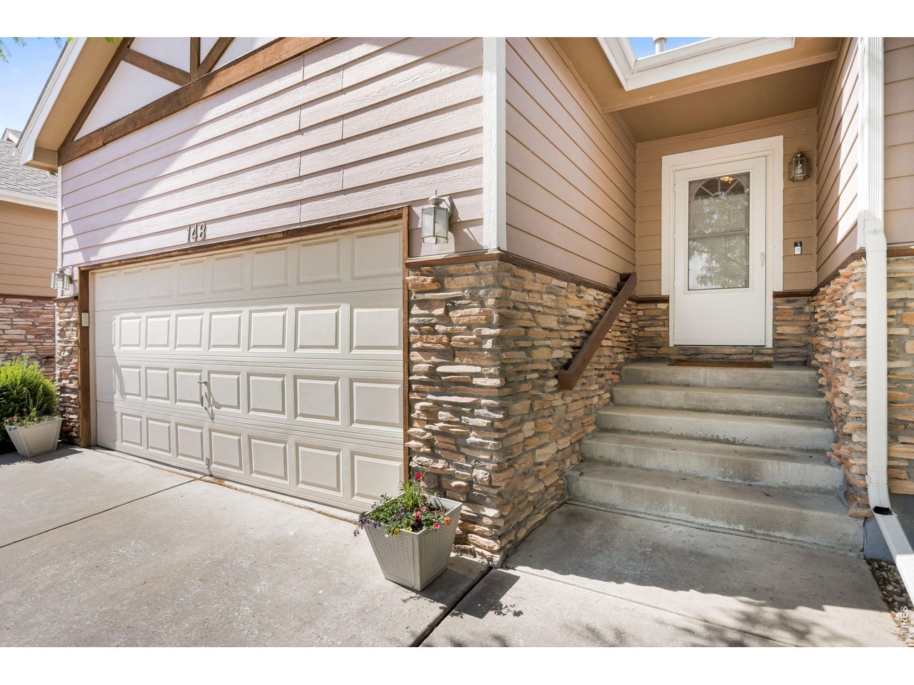 148 Beacon Way Windsor, CO 80550 - Photo 3 of 36 Close-up exterior detail of the front entry and garage featuring stacked stone accents, covered entryway.