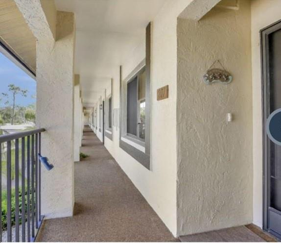 5419 Rattlesnake Hammock Road, Unit F204 Naples, FL 34113 - Photo 5 of 8 a view of a hallway with wooden floor and a living room