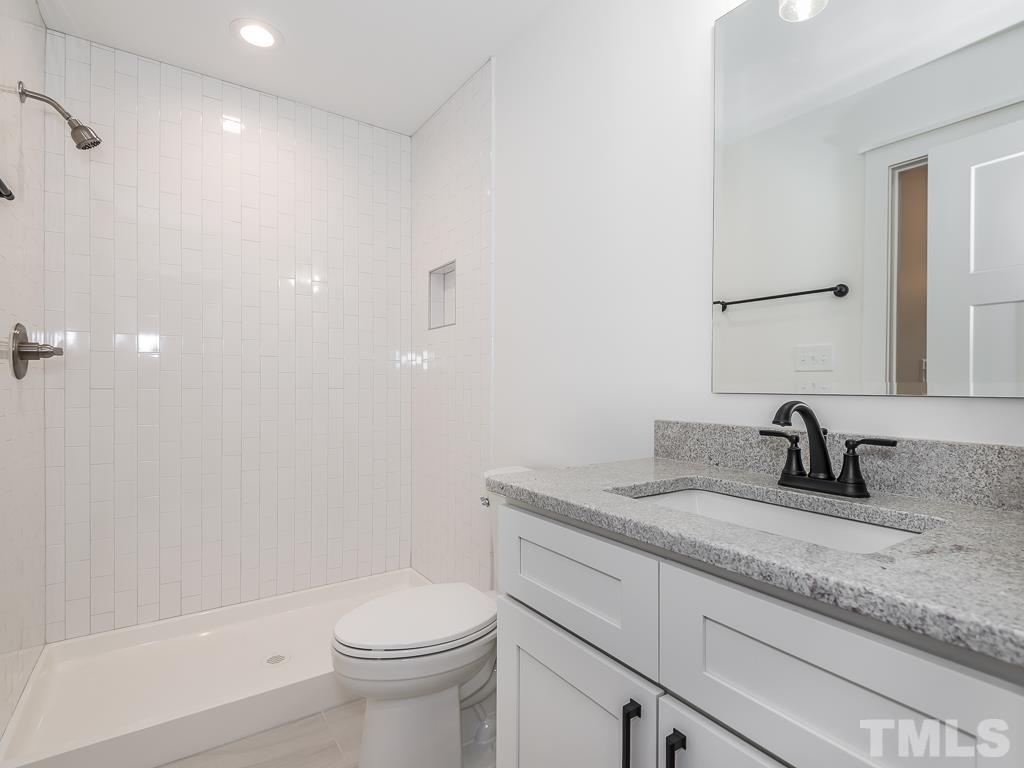 1703 Milton Road Durham, NC 27712 - Photo 34 of 39 a bathroom with a granite countertop sink a toilet and a mirror