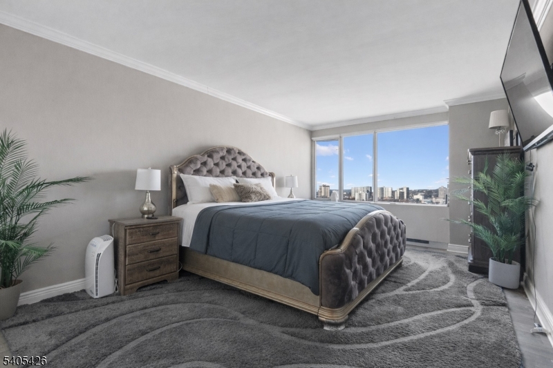 6 Horizon Road, Unit 2809 Fort Lee, NJ 07024 - Photo 11 of 19 a bedroom with a bed a mirror and a potted plant