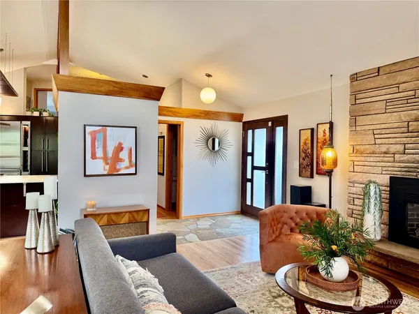 a living room with stainless steel appliances kitchen island granite countertop furniture and a wooden floor
