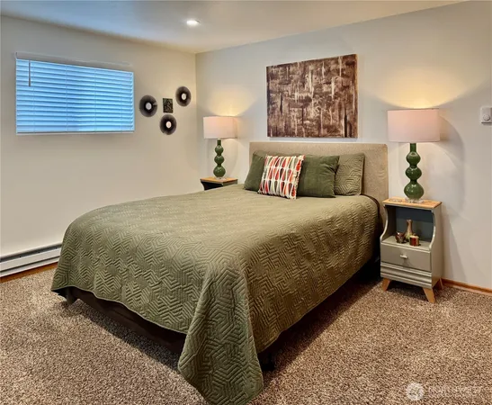 a bedroom with a bed a chair and painting on the wall