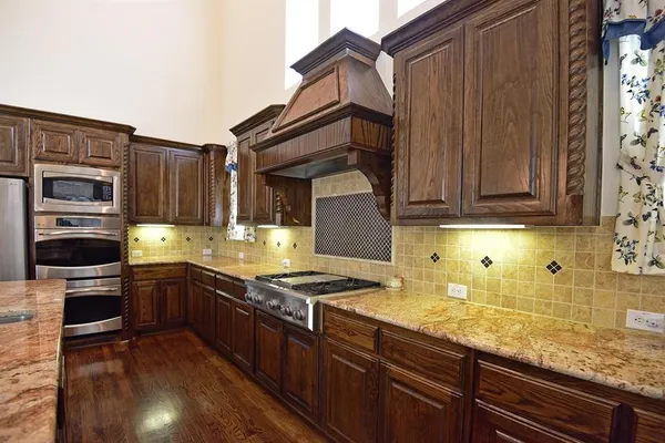 a kitchen with stainless steel appliances granite countertop a stove a sink and a microwave