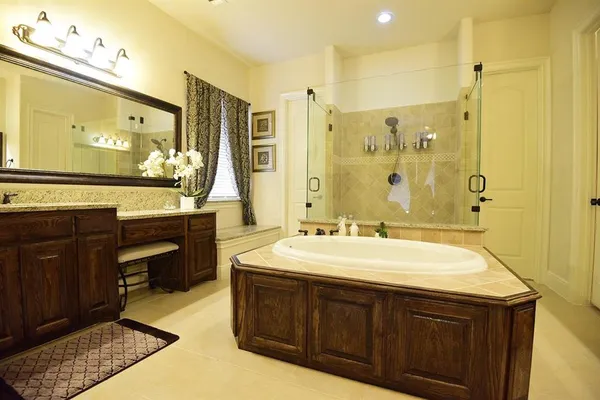 a spacious bathroom with a sink double vanity granite tub shower and a mirror