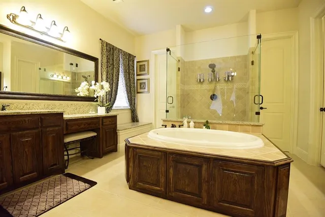 a spacious bathroom with a sink double vanity granite tub shower and a mirror
