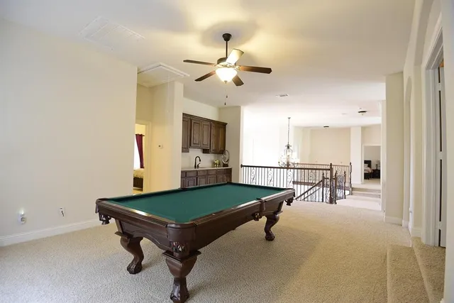 a living room with pool table and a ceiling fan