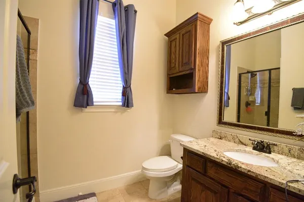 a bathroom with a granite countertop toilet sink and mirror