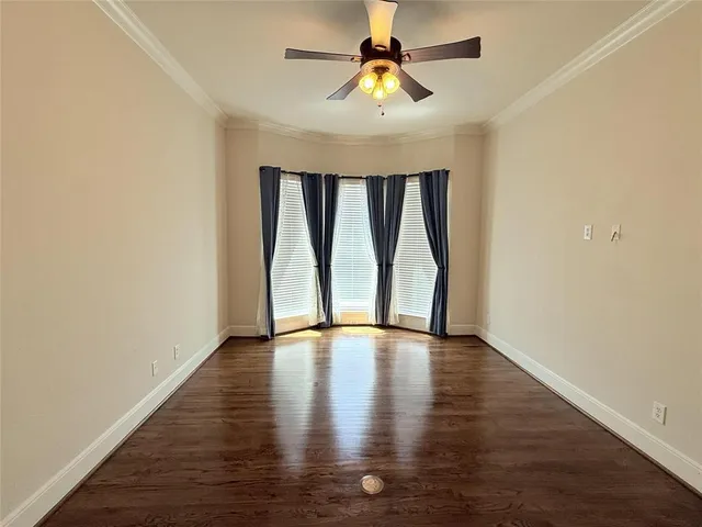 a view of an empty room with window and wooden floor
