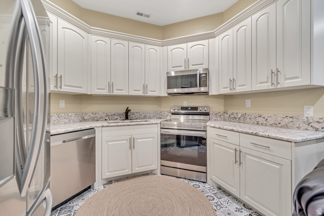 2543 East 700 South Springville, UT 84663 - Photo 49 of 73 Kitchen with stainless steel appliances, light stone countertops, and white cabinets