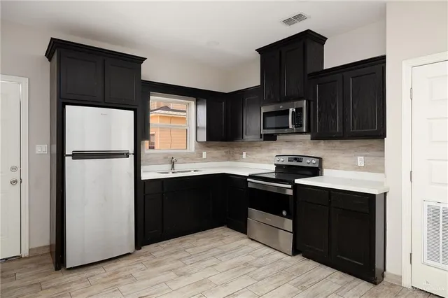 a kitchen with granite countertop wooden cabinets a refrigerator and a stove top oven