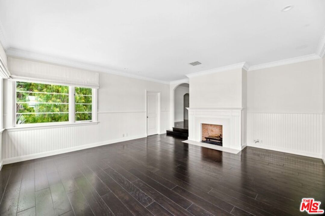 an empty room with wooden floor and a fireplace
