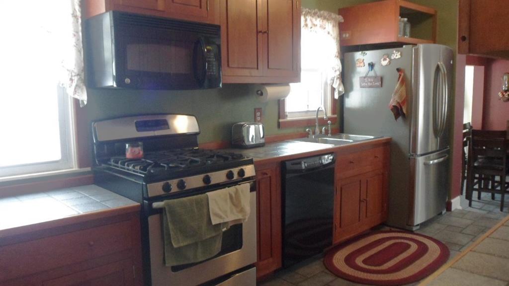 219 Easton Road Hermitage, PA 16148 - Photo 4 of 22 Kitchen has cherry cabinets and ceramic tile/slate look tile floor. Counter is matching tile. New gas stove and microwave, dishwasher and garbage disposal are included.