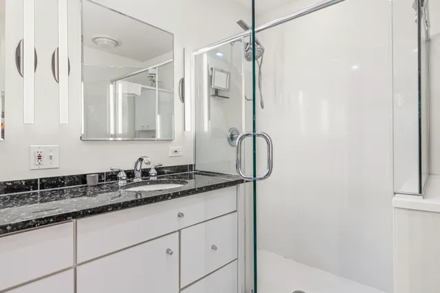 a bathroom with a granite countertop sink a mirror a vanity and a shower