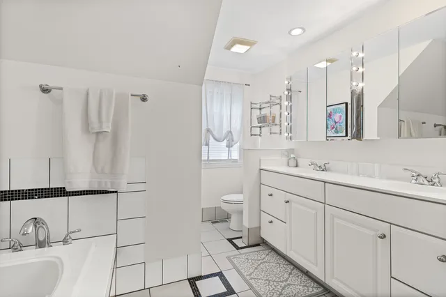 a spacious bathroom with a double vanity sink a mirror and a toilet